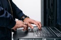 IT technician typing on laptop console in a data center server rack performing maintenance Royalty Free Stock Photo
