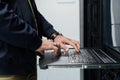 IT technician typing on a laptop in a server rack in a data center performing network maintenance Royalty Free Stock Photo