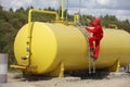 Technician in uniform climbing on large fuel tank