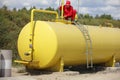 Technician in uniform working on large fuel tank