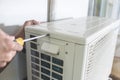 A technician unscrews the top hatch of the outdoor compressor unit of a Split type air conditioner. Repair or maintenance work Royalty Free Stock Photo