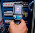 Technician use infrared thermal imaging camera to check temperature at fuse-box Royalty Free Stock Photo