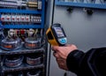 Technician use infrared thermal imaging camera to check temperature at fuse-box Royalty Free Stock Photo