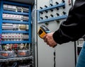 Technician use infrared thermal imaging camera to check temperature at fuse-box Royalty Free Stock Photo