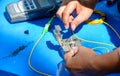 Technician useing cleaver cutting optic fiber on table with