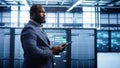 Technician walking in server room, doing checkup, inputting data on tablet Royalty Free Stock Photo