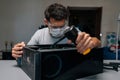 Technician wearing face mask and safety glasses cleaning computer case using small vacuum cleaner, demonstrating proper Royalty Free Stock Photo