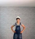 Technician woman ware white helmet with grey T-shirt and denim jeans apron dress standing akimbo.