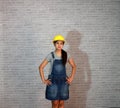 Technician woman ware white helmet with grey T-shirt and denim jeans apron dress standing akimbo.