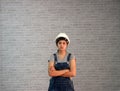 Technician woman ware white helmet with grey T-shirt and denim jeans apron dress standing straight angle and hugging chest.