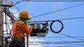 Technician on wooden ladder checking fiber optic cables in internet splitter box on electric pole against blue sky