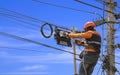 technician on wooden ladder is installing fiber optic system in internet splitter box on electric pole