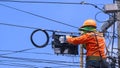 Technician on wooden ladder is working to install fiber optic and splitter box on power pole against blue sky Royalty Free Stock Photo