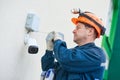 Technician worker installing video surveillance camera on wall