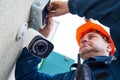 Technician worker installing video surveillance camera on wall