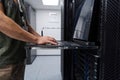 It technician working on a laptop console in a data center server rack performing network maintenance and monitoring Royalty Free Stock Photo