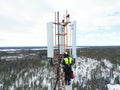 Technician working on a telecommunications tower against the background of a snowy forest. Royalty Free Stock Photo