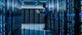 An IT technician works on a laptop in a big data center full of rack servers. He runs diagnostics, maintains and sets up Royalty Free Stock Photo