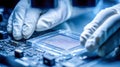 A technician works with a microchip on a printed circuit board wearing anti-static gloves, an advanced manufacturing process Royalty Free Stock Photo