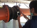 Coupling flange. The worker tightens the bolts on the Rubber Expansion Joint with a wrench for Cooling Tower.