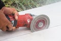 Technicians are using a hand grinding machine cuts sheets of cement board.