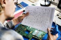 Technicians working holding electronics circuit guide paper