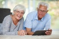 We are a techno friendly couple. a senior couple lying on the floor while using a digital tablet.