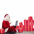 Technological Santa Claus sitting with laptop buys Christmas gifts with e-commerce