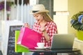 Technologies make shopping easier. Beautiful young woman with shopping bags using her laptop computer with smile while standing at Royalty Free Stock Photo