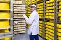 Inspector makes notes in the sheet at the cheese warehouse Royalty Free Stock Photo