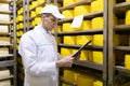 Inspector makes notes in the sheet at the cheese warehouse Royalty Free Stock Photo