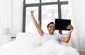 Happy indian man with tablet pc in bed at home Royalty Free Stock Photo