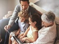 Technology bringing young and old together. an elderly couple and their grandchildren sitting together and using a Royalty Free Stock Photo