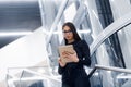 Technology, business and corporate concept - happy woman or student with tablet pc computer standing on stairs at modern Royalty Free Stock Photo