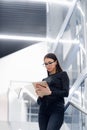 Technology, business and corporate concept - happy woman or student with tablet pc computer standing on stairs at modern Royalty Free Stock Photo