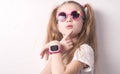 Technology for children: a girl wearing pink glasses uses a smartwatch.