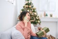 Technology. Communication. Christmas. Young woman is holding a gift box, talking on the mobile phone and smiling while sitting Royalty Free Stock Photo