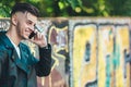 Technology and communication. Closeup young fashion man talking on mobile cell phone using smartphone outdoor graffiti Royalty Free Stock Photo