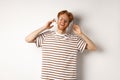 Technology concept. Happy redhead man listening music in headphones and singing along, standing over white background Royalty Free Stock Photo