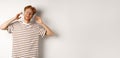 Technology concept. Happy redhead man listening music in headphones and singing along, standing over white background Royalty Free Stock Photo