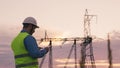 technology concept with high voltage power lines. electrical engineer helmet digital tablet sunset. power engineer power Royalty Free Stock Photo