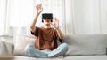 Technology Concept The man with his brown T-shirt and light blue jeans wearing a virtual reality headset while sitting on the sofa Royalty Free Stock Photo