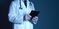 Technology in healthcare: doctor\'s digital tablet, blue background, face concealed.