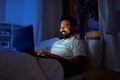 indian man with laptop in bed at home at night Royalty Free Stock Photo