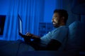 indian man with laptop in bed at home at night Royalty Free Stock Photo