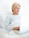 Technology keeps her connected with her loved ones. Elderly female patient browses a laptop from her hospital bed.