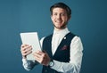 Technology keeps me ahead of the curve. Studio shot of a handsome young businessman using a tablet against a blue Royalty Free Stock Photo