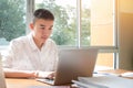 Technology Learning concept: Asian Young man student learning and check timetable for projected in laptop computer at busy table