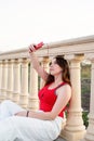 Teenage girl sitting next to column making selfie and listening to the music in the park at sunset Royalty Free Stock Photo