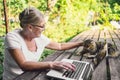 Happy senior old woman with home cat working online with laptop computer outdoor Royalty Free Stock Photo